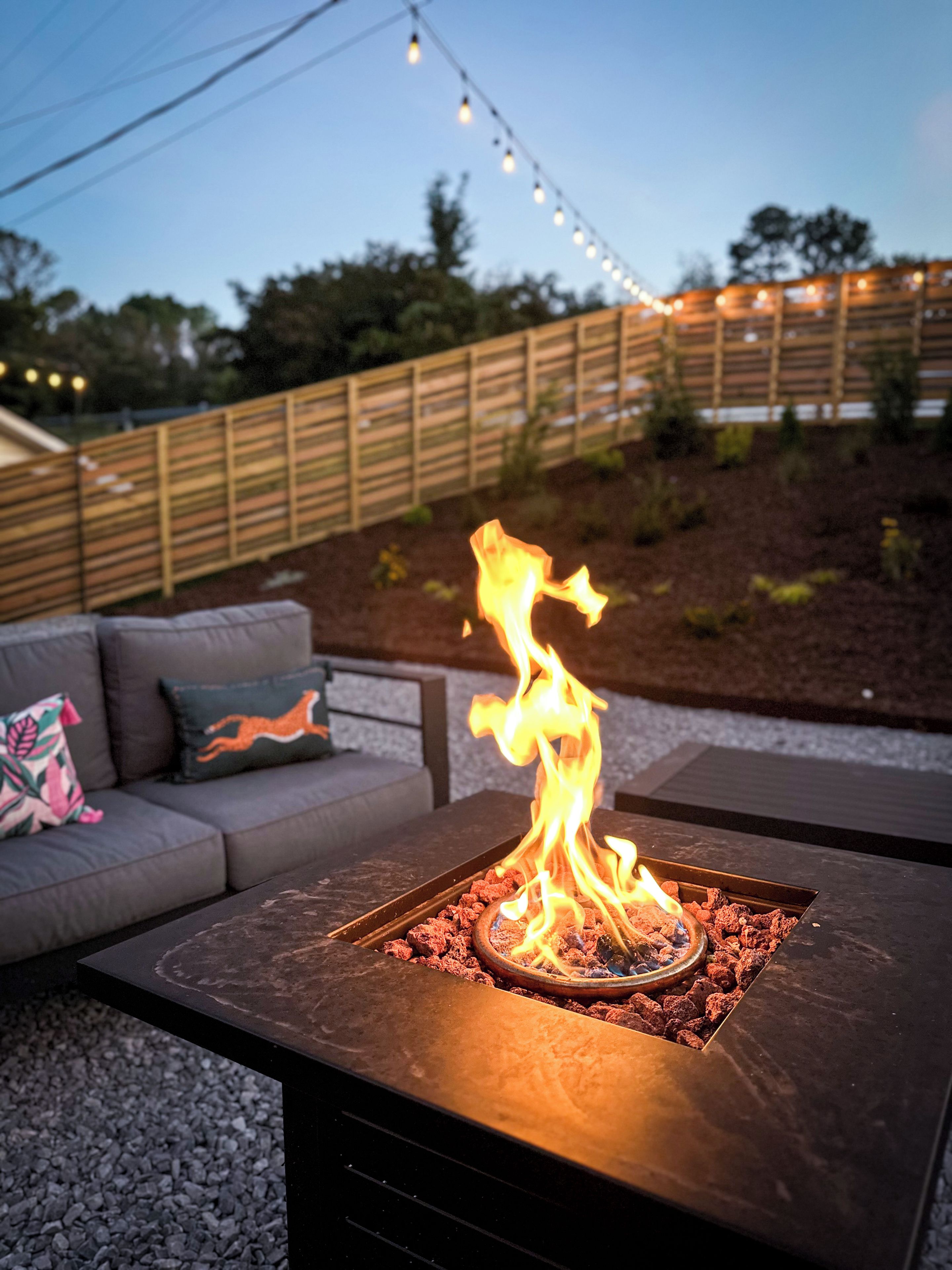 A fire feature with a metal grate, surrounded by a dark-colored table.