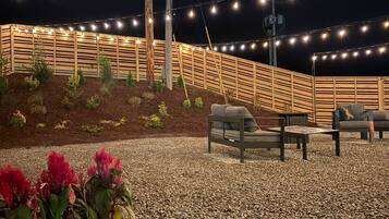 A patio area with a wooden fence, string lights, and outdoor seating.