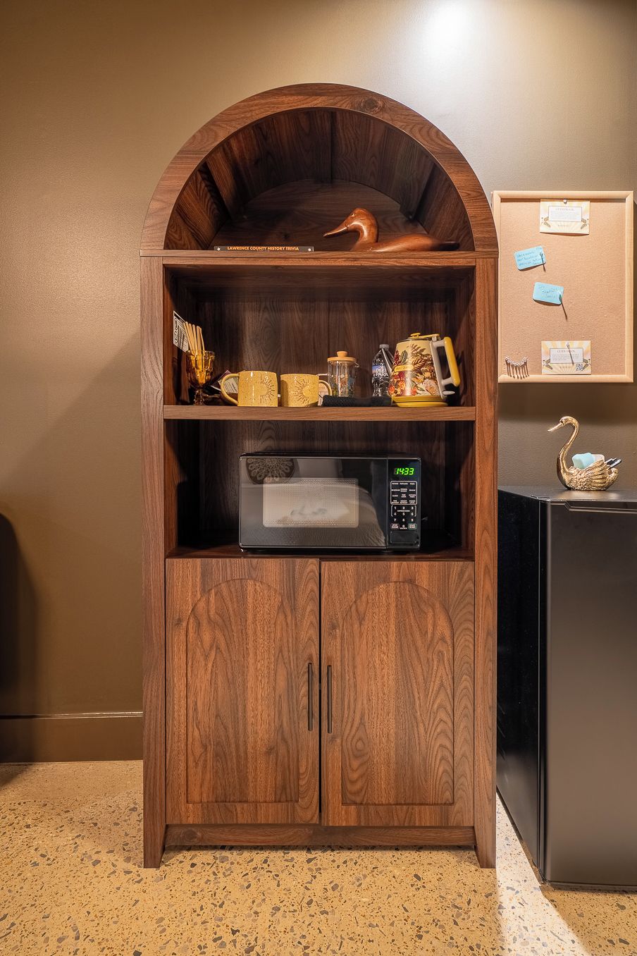 A wooden cabinet with a microwave and a decorative swan.