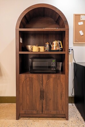 Ein Holzschrank mit einer Mikrowelle und einer Kaffeemaschine darauf.