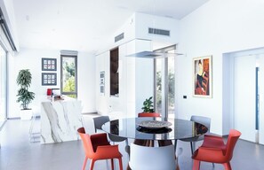 A modern dining area with a round table, red chairs, and a view of the outdoors. - Exquisite Nikiana Villa with Sea Views and Pontoon Access near Tavernas (Lefkada)