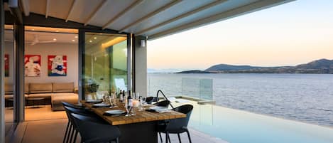 A modern dining area with a view of the sea, a sofa, and artwork on the wall.