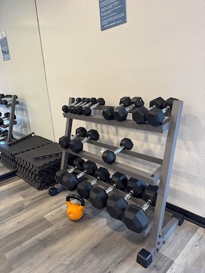 A gym with a rack of dumbbells and a kettlebell on the floor. - Modern 2BR Near NASA: Washer/dryer, Pool, Balcony (Houston)