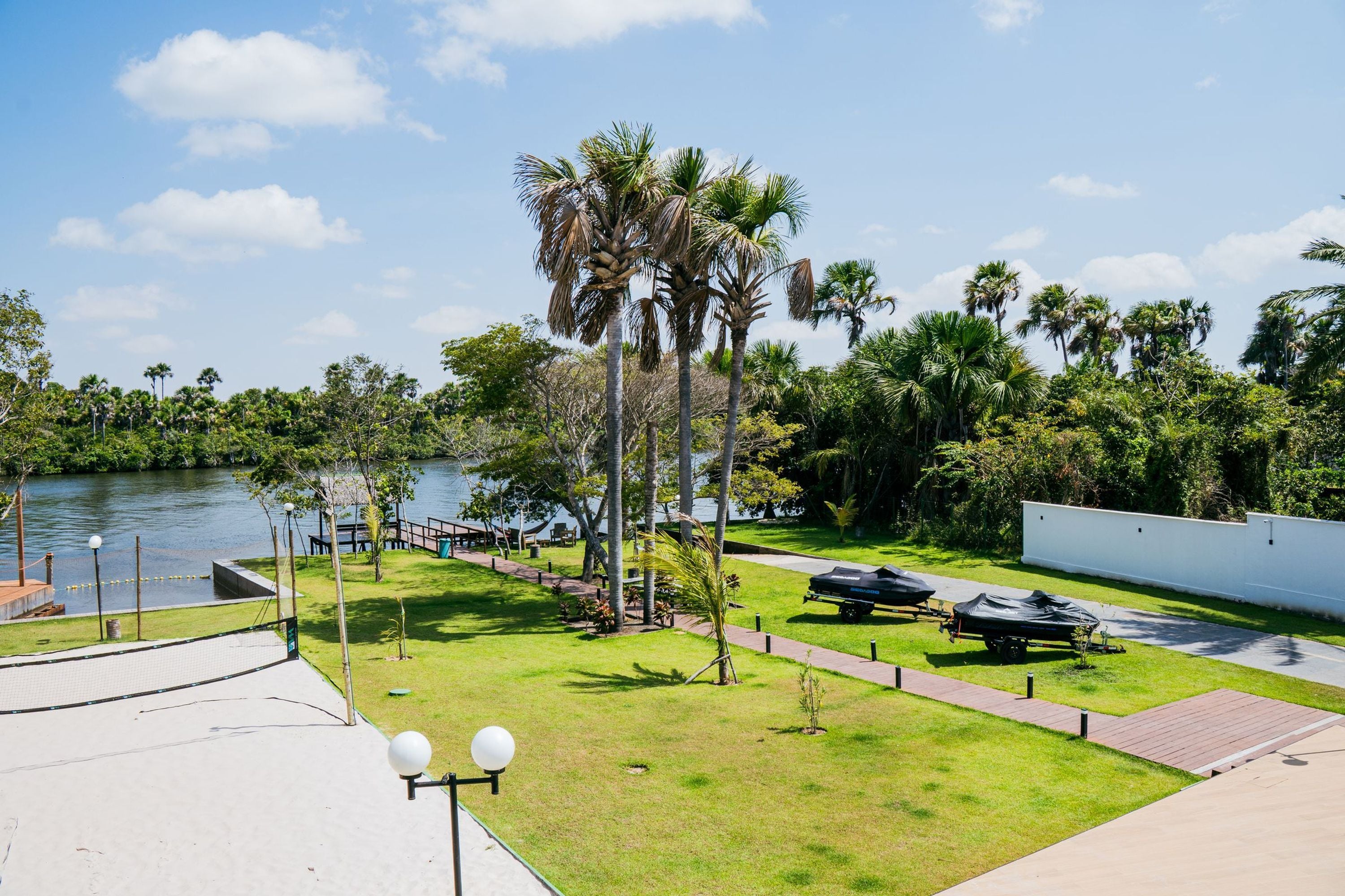 A waterfront park with palm trees, a walking path, and a boat trailer.
