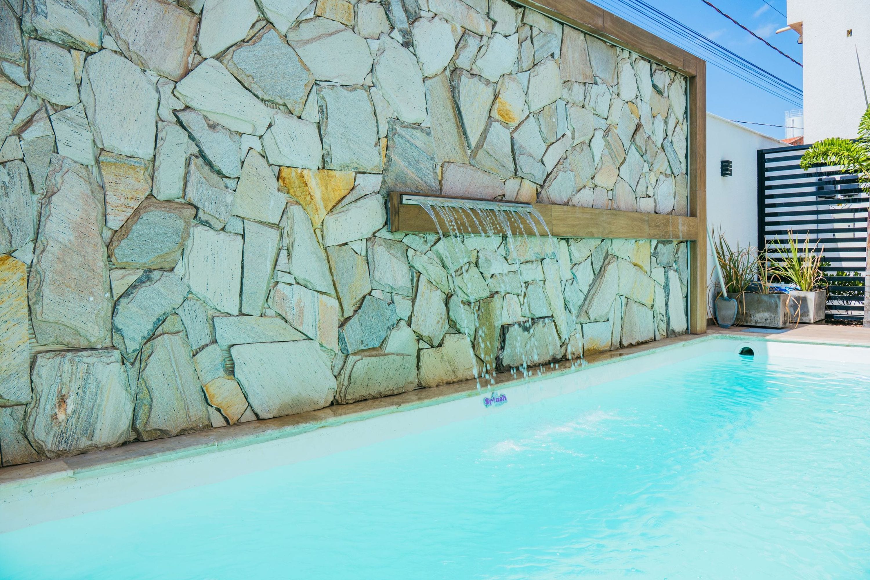Una piscina con pared de piedra y fuente de agua.