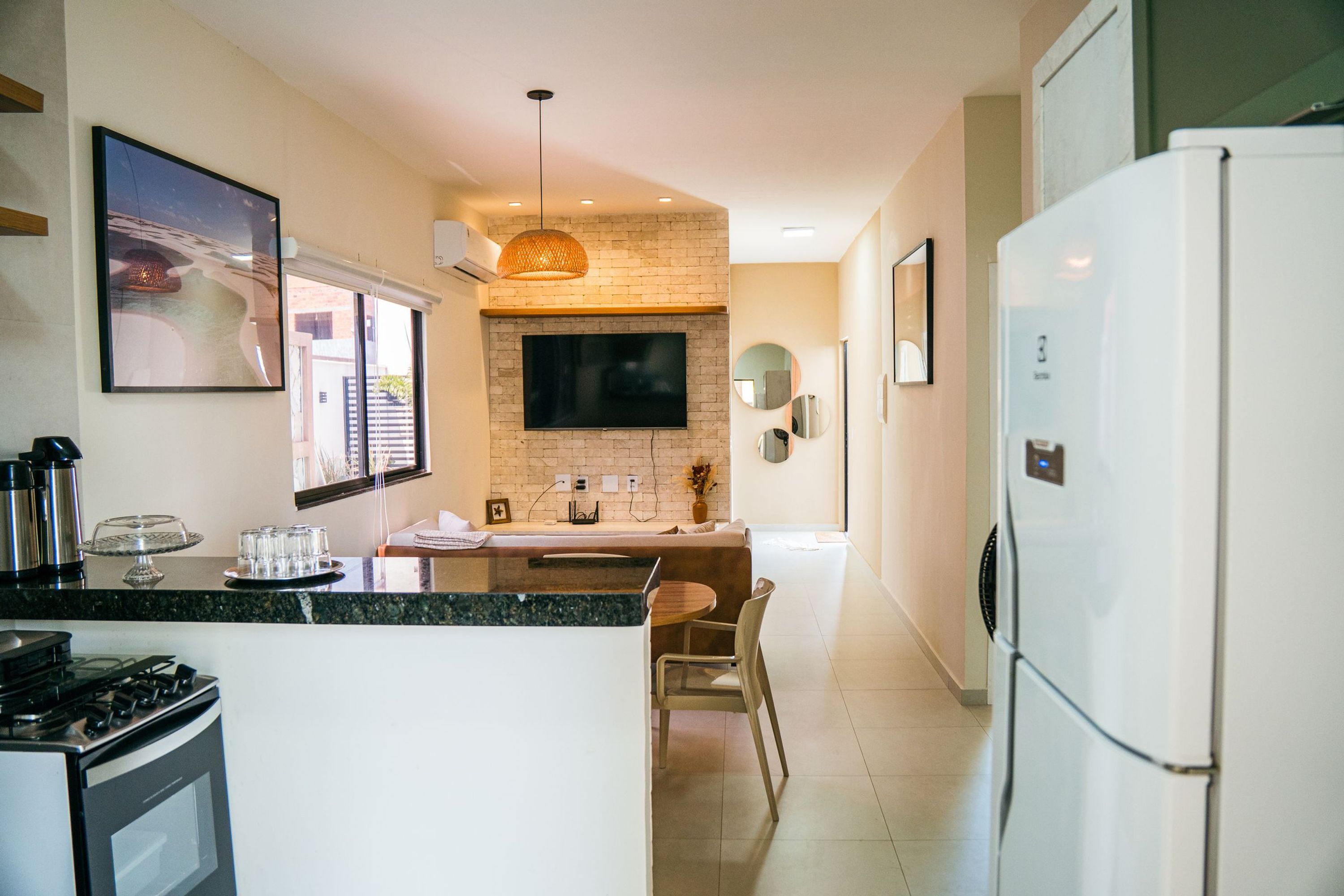 A modern kitchen with a large island, a built-in oven, and a flat-screen TV mounted on a brick wall.