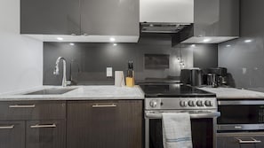 Une cuisine moderne avec des meubles de couleur bois foncé, une cuisinière en acier inoxydable et un four Danby noir.