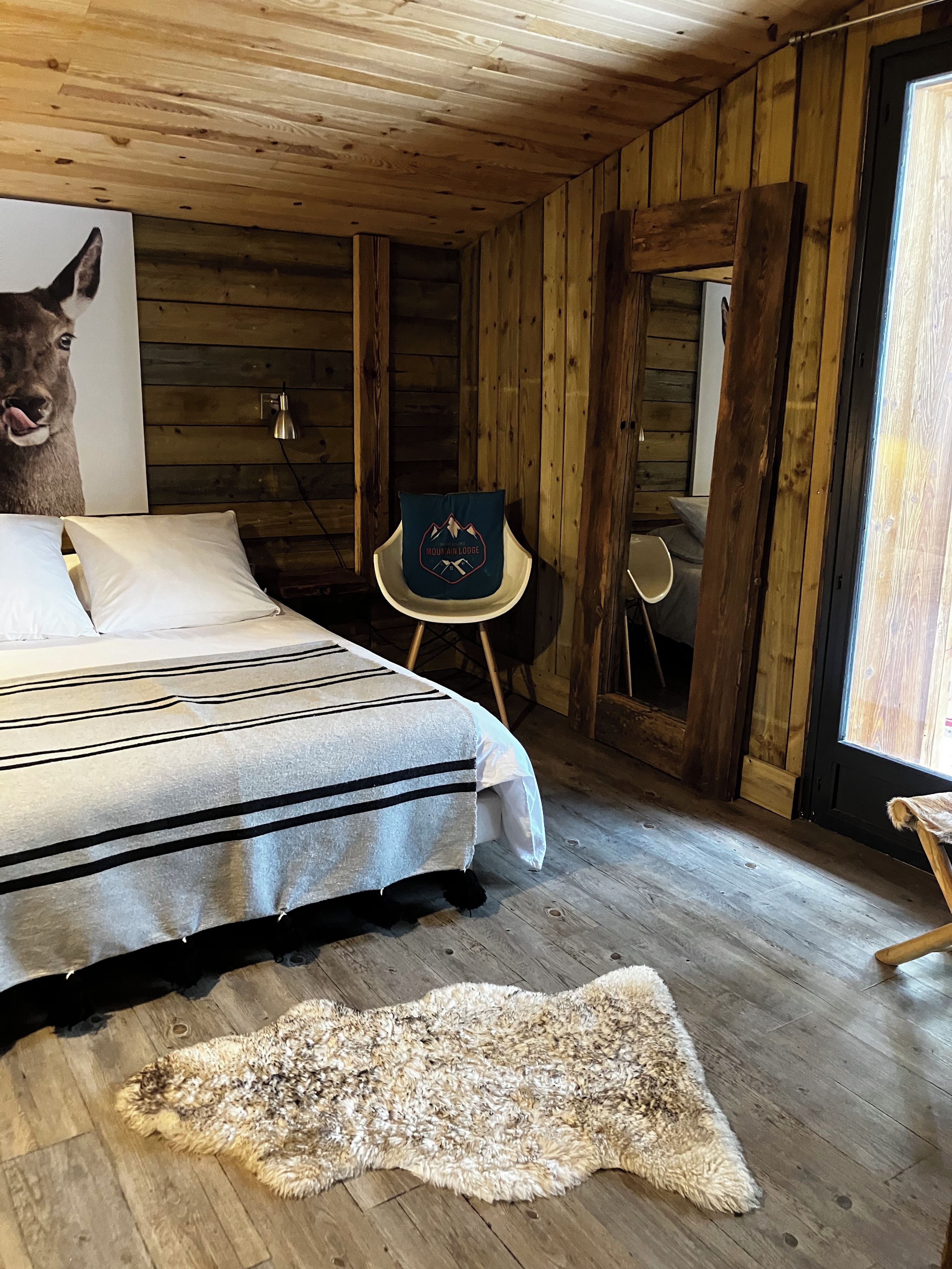 Een houten chalet van binnen met een bed, een stoel en een vloerkleed.