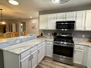 A kitchen with white cabinets, a stainless steel stove, and a microwave.