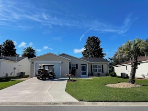 A single-story house with a garage, a lawn, and a palm tree.