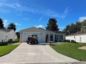 A residential driveway leading to a garage with a golf cart parked inside.