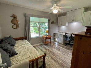 Un dormitorio con cama, escritorio y ventana.