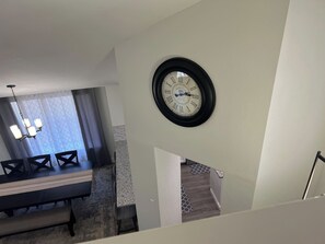 A dining area with a chandelier, a clock on the wall, and a staircase leading to another level. - Cozy home, Pool access between Sea-word & Sixflags (San Antonio)