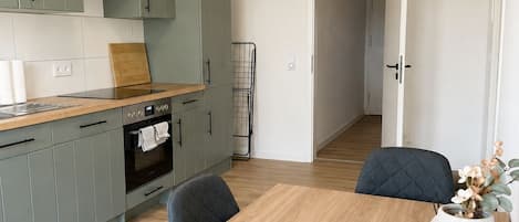 A modern kitchen with grey cabinets, a wooden countertop, and a dining table with chairs.