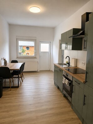 A modern kitchen with a built-in oven, a sink, and a window overlooking a courtyard. - Mühlhausen Ground Floor Apartment for Workers and Vacationers (Mühlhausen)