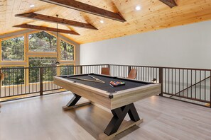 A pool table in a room with wooden beams and large windows overlooking a forest. - The West Nest - Ellijay,GA (Ellijay)