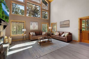 A spacious living room with a large window, a fireplace, and a cozy seating area. - The West Nest - Ellijay,GA (Ellijay)