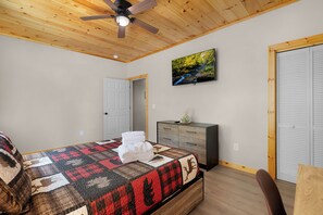A bedroom with a bed, a dresser, a ceiling fan, a painting, and a closet. - The West Nest - Ellijay,GA (Ellijay)