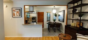 A modern kitchen with a central island, dining area with chairs, and a bookshelf with decorative items. - WFH Retreat at Jackson Market (Culver City)