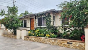 A residential house with a stone facade, a wooden door, and a garden with various plants and flowers. - WFH Retreat at Jackson Market (Culver City)