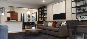A modern living room with a sofa, coffee table, and a dining area with chairs and a table. - WFH Retreat at Jackson Market (Culver City)