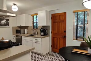 A compact kitchen with white cabinets, a microwave, a coffee maker, and a stove. - WFH Retreat at Jackson Market (Culver City)