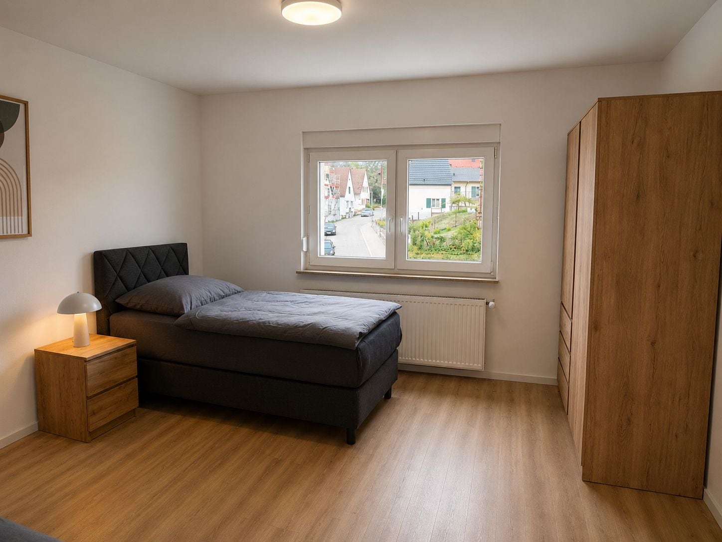 Un dormitorio con cama, mesita de noche, lámpara, ventana con vistas y armario.