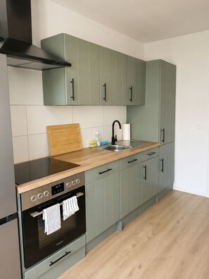 A modern kitchen with grey cabinets, a wooden countertop, a stainless steel sink, and a built-in oven. - Mühlhausen OG Apartment for Workers and Vacationers (Mühlhausen)