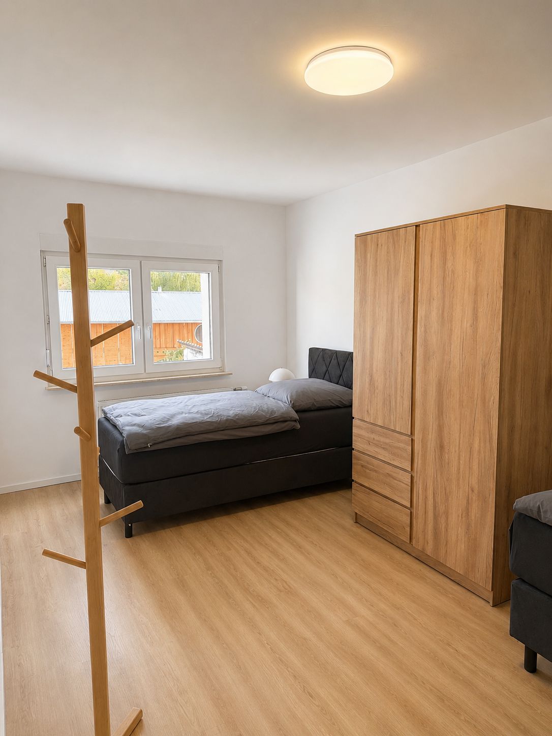 A bedroom with a bed, a wardrobe, and a window.