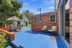 En patio med udendørs møbler, et overdækket siddeområde og en bygning med murstensfacade og skydedør.
