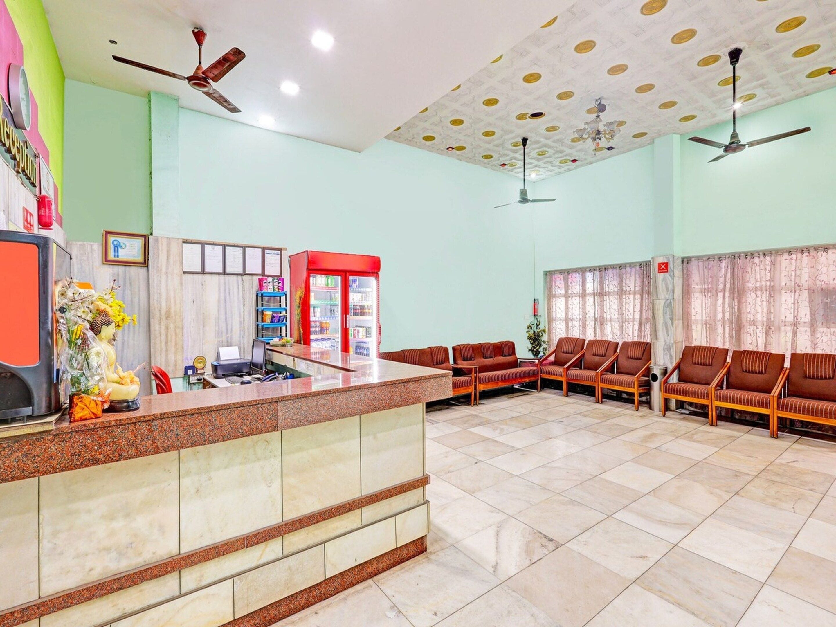 Un área de recepción con mostrador, asientos, ventiladores de techo y techo estampado.
