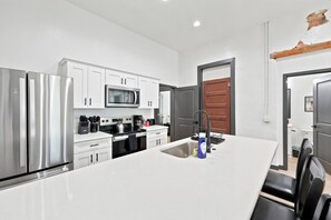 Una cocina moderna con electrodomésticos de acero inoxidable, armarios blancos y una isla central con un lavamanos.