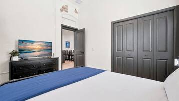 A bedroom with a bed, a dresser, a painting, and a closed door.