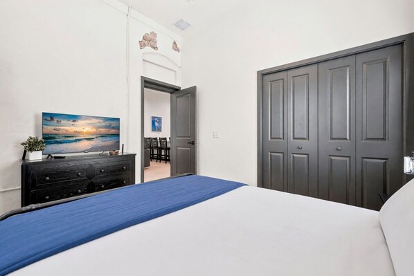 Un dormitorio con cama, cómoda, un cuadro y una puerta cerrada.