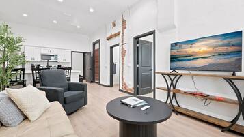 A modern living room with a sofa, armchair, coffee table, and a TV on a stand.