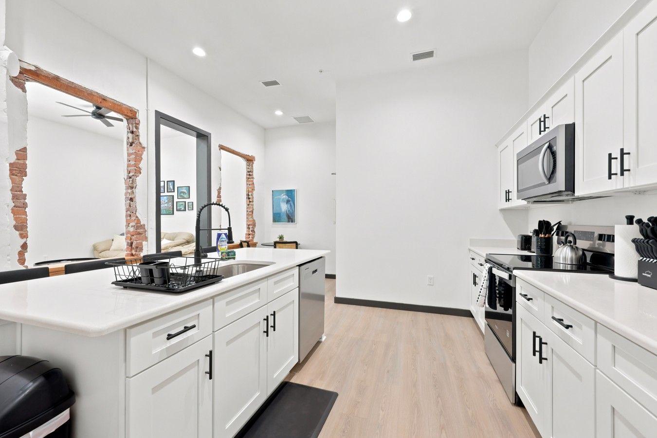 A modern kitchen with white cabinetry, a black countertop, and a stainless steel range hood.