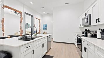 A modern kitchen with white cabinetry, a black countertop, and a stainless steel range hood.