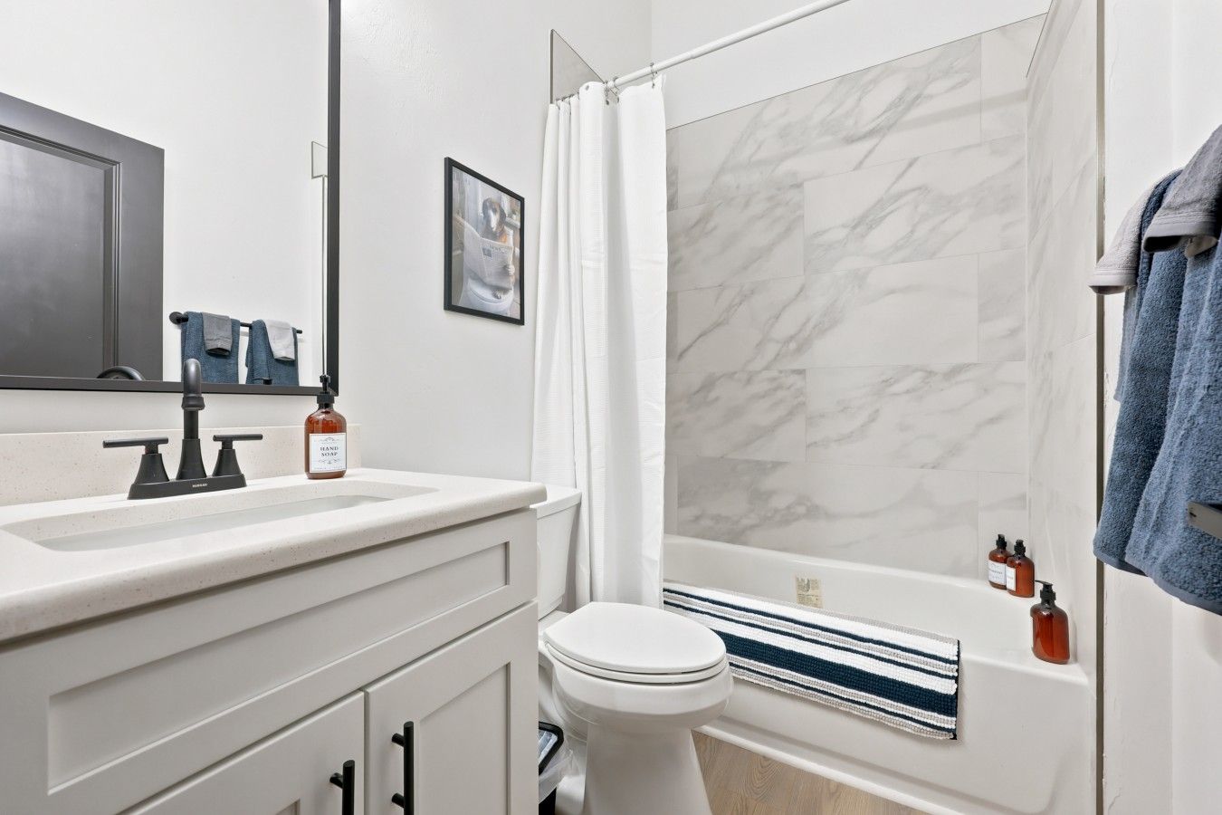 A modern bathroom with a white sink, a toilet, and a bathtub with a shower curtain.