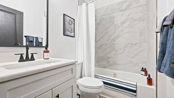A modern bathroom with a white sink, a toilet, and a bathtub with a shower curtain.