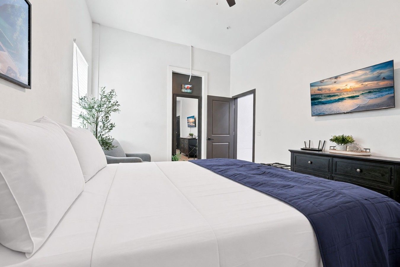 A bedroom with a bed, a dresser, a door, and a painting on the wall.
