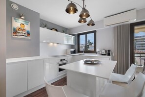 Une cuisine moderne avec des meubles blancs, un îlot central et des luminaires suspendus.