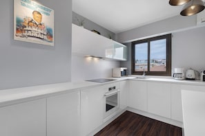 A modern kitchen with white cabinetry, a built-in oven, a microwave, and a window with a view of buildings. - Palm Beach Apartment Near Beach with Private Terraces, Parking, Wi-Fi, and Air Conditioning (Cannes)