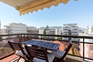 En balkon med et træbord og stole, med udsigt over et bybillede med moderne bygninger.