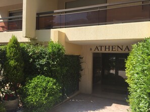 Entrada de un edificio con un letrero que dice 'ATHENA' y un camino de acceso con puerta de reja.