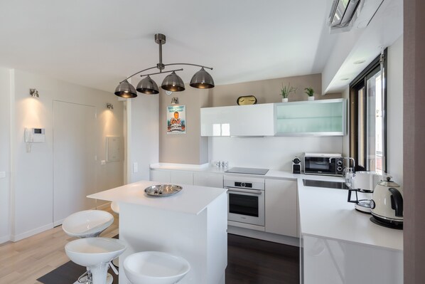 Una cocina moderna con armarios blancos, horno Bosch, microondas y cafetera.