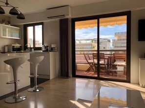 Una cocina moderna con comedor, un amplio ventanal corredero a un balcón y vistas de la ciudad.