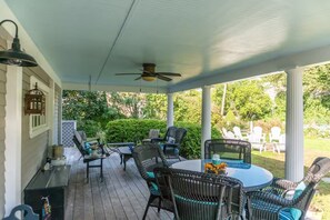 Un patio couvert avec des meubles d’extérieur, un ventilateur de plafond et une vue sur un jardin.