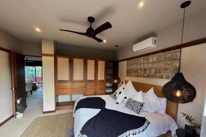Ein Schlafzimmer mit Bett, Deckenventilator, Klimaanlage und einer Pendelleuchte.