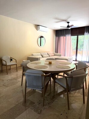 A dining area with a round table, chairs, and a sofa. - Brand New Spacious 4-bedroom condo in lovely Cozumel with Jacuzzi g12 (Cozumel)