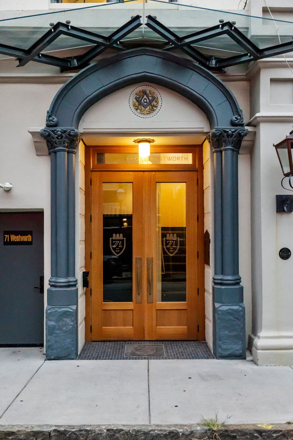 A hotel entrance with a wooden door, a glass entrance, and a sign above the door.